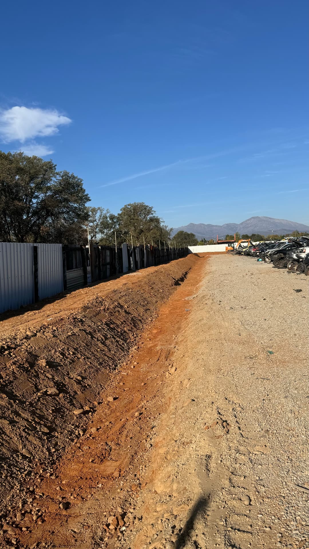 Drainage swale trench controlling stormwater runoff along a fence line